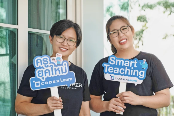 ภาพลูกค้าที่ใช้งานระบบ CodexLearn ครูน้ำ ชิดชนก และ ครูวัน วันวิการ์ ผู้บริหารและครูสอนโรงเรียนกวดวิชา Together ที่กำลังถือป้าย (ครูยุคใหม่ codexlearn) และ (Smart Teaching codexlearn) สำหรับประกอบการรีวิว